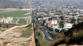 A small fence separates densely-populated Tijuana, Mexico, right, from the United States in the Border Patrol's San Diego Sector. Construction is underway to extend a secondary fence over the top of this hill and eventually to the Pacific Ocean