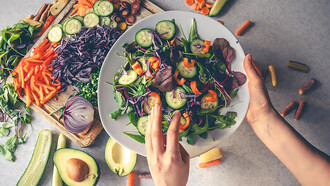 Female hands holding a bowl of vegan salad with fresh vegetables 