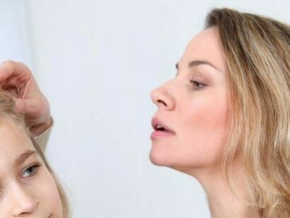 Madre buscando piojos en el cabello de su hija