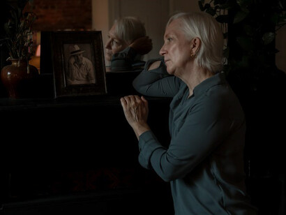 In a moment of poignant reflection, the elderly woman gazes upon a photograph, her heart heavy with grief, her eyes a wellspring of sorrow, as she grapples with her profound sense of loss