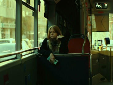 A blonde woman rides the bus alone during her commute