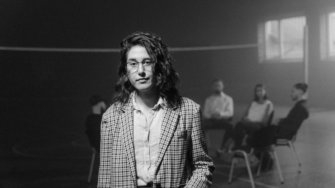 Amidst discussions of toxic masculinity and its repercussions at a support group, a woman's solemn gaze underscores the gravity of how societal conditioning perpetuates harmful gender stereotypes