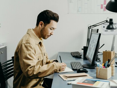 An architect in brown long sleeves using a computer to create a 3D design in a modern workspace