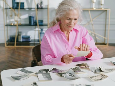 Mulher observa fotos antigas. Eu, por vezes, sinto o cheiro dela, não sei como e nem porquê, mas sinto. Outras tantas vezes, chego a sentir seu delicado toque em meu rosto com um sorriso, me dizendo para seguir em frente