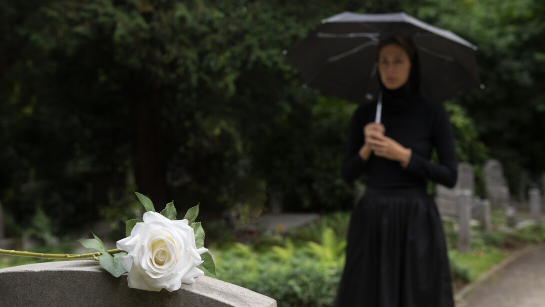 A young woman in a graveyard holding a white rose