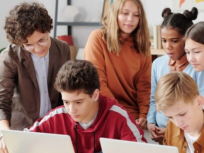 Professora orienta um aluno sobre ser criativo ao modelar a linguagem de programação que estão desenvolvendo