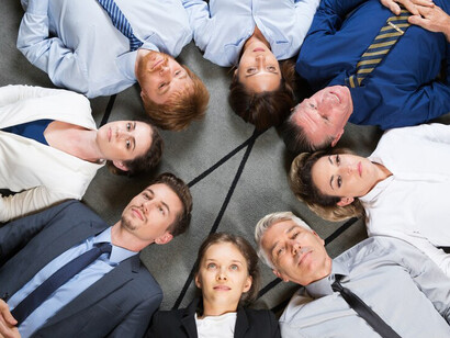 A diverse business team lying on the floor and clapping, symbolizing corporate inclusion, intersectionality in social justice, and the importance of diversity within the workplace