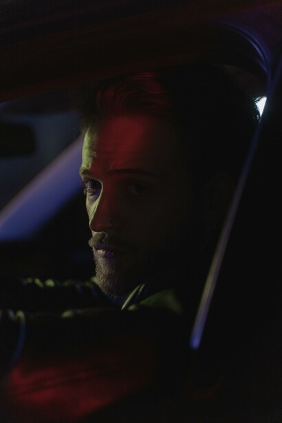 A man looking out a car window at night 