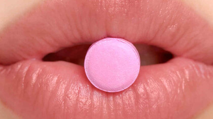 Una mujer se dispone a tragar una pastilla