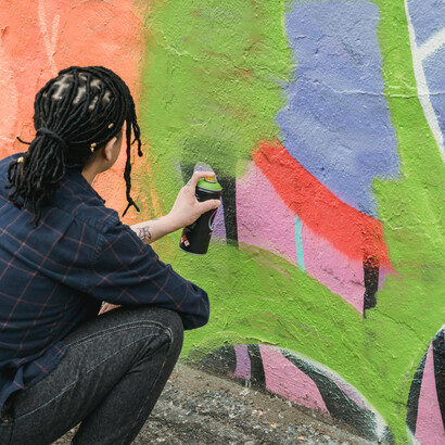 Joven realizando un grafiti con aerosol. En algunos casos, estas creaciones, construidas y pensadas, son encargos específicos de los comerciantes para llamar clientes