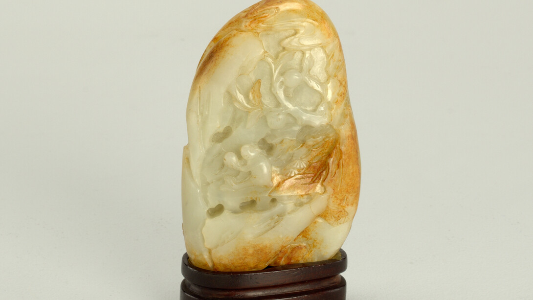 Montaña de jade con soporte: nefrita de color blanco verdoso con manchas de color marrón anaranjado talladas en el anverso para representar un mono sosteniendo la inmortalidad del melocotón y sentado debajo de un árbol en el que crecen los melocotones y soporte de palisandro de cuatro patas. Cobertizo de piedra en las montañas