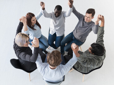 Overhead view of a human circle with raised hands, illustrating cooperation and social connection