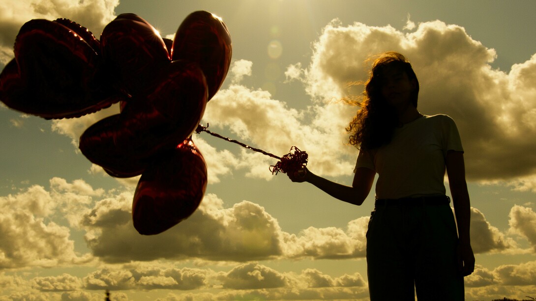 A woman holding a bunch of red heart-shaped balloons