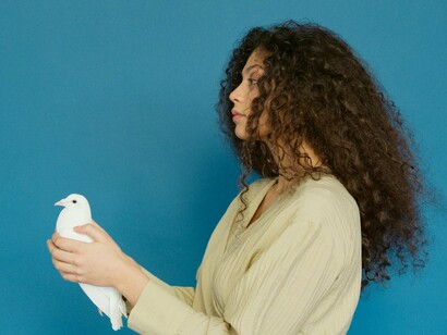 A woman carefully cradling a white dove in her hands, representing the gentle balance between emotional connection and inner peace