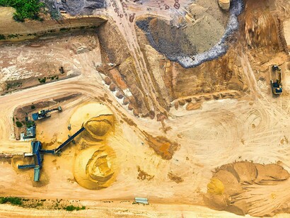 Vista aérea de uma área de mineração com maquinário pesado em operação. O crescimento dos megaprojetos extrativos em Moçambique aumenta a pressão por práticas transparentes de sustentabilidade e governança