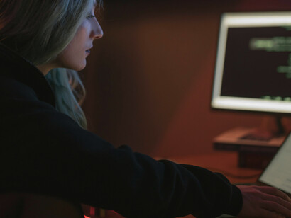 A woman typing on a keyboard, working as a programmer