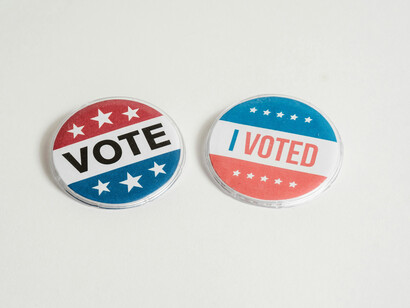 Two pins, one reminding people to vote and another one given to those that did