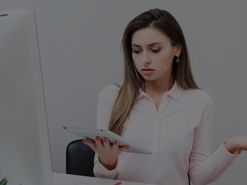 A frustrated female screenwriter grapples with her tablet while seated at her desk