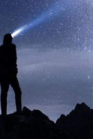 A human figure contemplates a falling star and the night sky