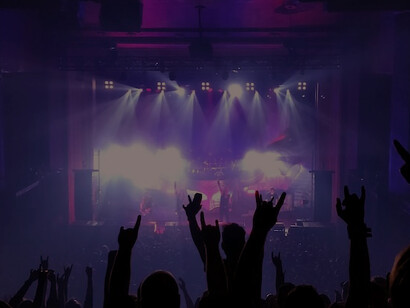 A crowd of enthusiastic concertgoers enthusiastically raises their hands in unison