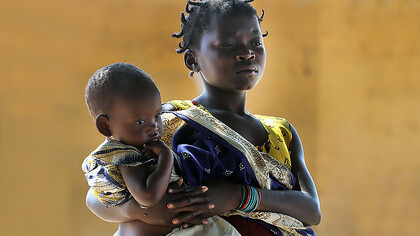 Young girl tenderly holding a baby in Mozambique, evoking poverty in a setting