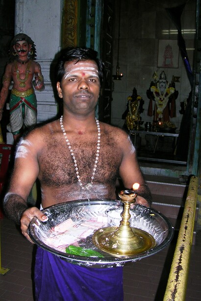 Batu Cave. Sacerdote offre piccolo involucro di carta contenente la cenere del “ritrovamento”.