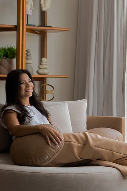 A woman is sitting on the couch in a space featuring minimalist architecture, with clean lines and natural materials incorporated into the design
