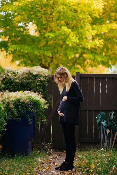 A young mother standing near a brown wooden fence, contemplating the challenges ahead