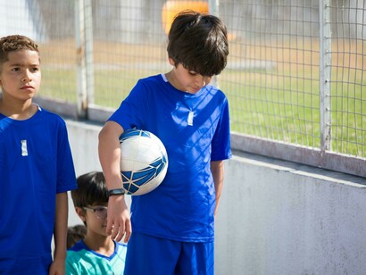 Children in Portugal walking up the stairs toward a football field during a youth academy training session
