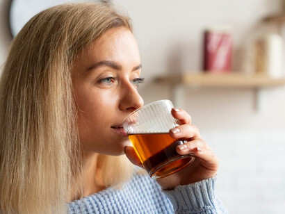 A woman enjoying a glass of kombucha