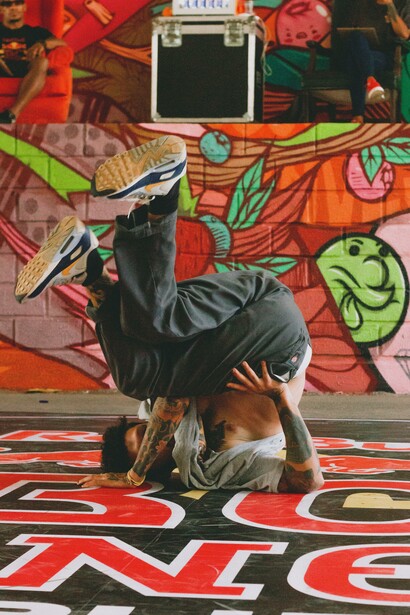 Man breakdancing in front of a graffiti wall