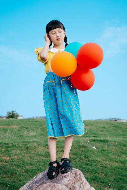 A young girl standing alone with a cluster of balloons, reflecting the uncertainty of holding on to connection while fearing it may disappear