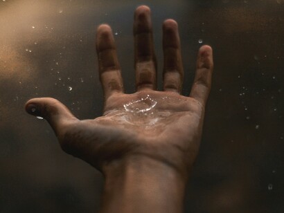 An open hand under the rain, humans opening themselves to a higher faith