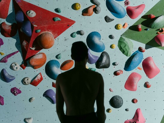 A silhouette of a man standing before a climbing wall, preparing to climb