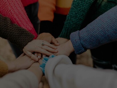A group of people putting their hands together palms facing down to symbolize the strong bond of their team