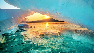 Sunlight shining through thinning glaciers at sunrise, representing the accelerating effects of a warming planet