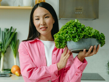 A woman holding a bowl of fresh lettuce, symbolizing vegan food, mindful nutrition, and a balanced plant-based lifestyle