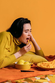 Woman lying on orange floor looking at television