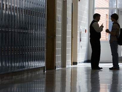 Profesor y alumno charlando al final de un pasillo