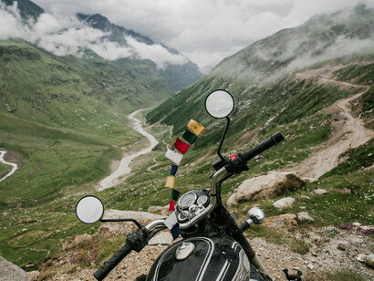 A parked motorcycle set against the backdrop of green mountains in the Himalayas of Nepal