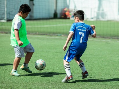 Two young footballers battling for possession, symbolising the competitive spirit that drives continual improvement