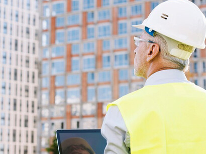 A construction worker in a helmet at a site featuring AI-driven urban development, sustainable architecture, and smart buildings