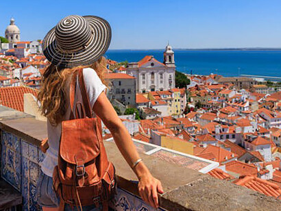 A female tourist gazes out at a panoramic cityscape viewpoint, taking in the breathtaking scenery of Porto, Portugal