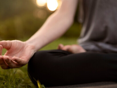 A woman meditating in nature, surrounded by spiritual energy, with a visible energy field and a sense of inner strength and positive energy flowing through her