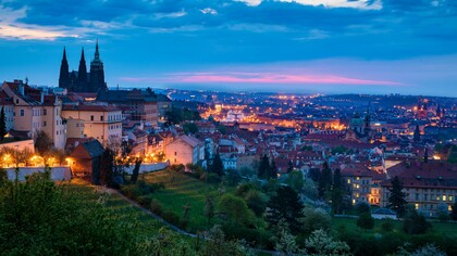 Prague’s historic rooftops and landmarks illuminated against the twilight sky, representing the city’s magical character