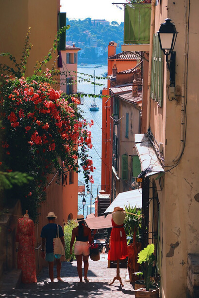 The vibrant streets of Nice, France, as people stroll among beautiful red flowers under the radiant daytime sun, immersing yourself in the picturesque scenery of this iconic destination on the French Riviera