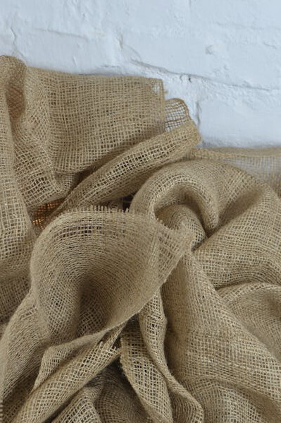 Textured sackcloth with delicate fibers lying on a clean white background, symbolizing the raw materials behind ethical and environmentally friendly clothing