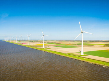 Wind turbines generating clean electricity along the shoreline of a wind farm.