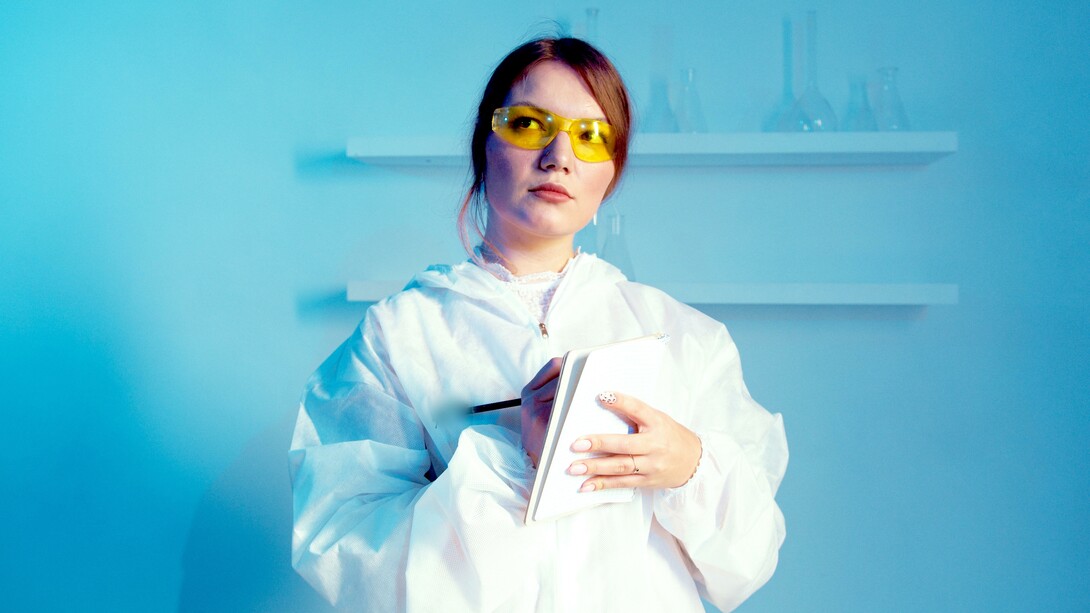 Uma mulher cientista vestindo jaleco enquanto segura um caderno