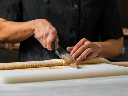 Cozinheiro prepara massa. Na hora de preparar o mise en place desse prato o cozinheiro provavelmente irá picar tudo que fará parte do preparo e armazenar, limpar e armazenar o peixe que será grelhado, etc. Tudo é pré-preparado de maneira que na hora do serviço tudo possa ser servido rapidamente